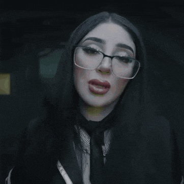 a woman with long black hair wearing glasses and a black tie .