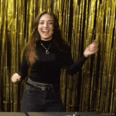 a woman in a black shirt is dancing in front of a gold curtain with ritualas written on the bottom