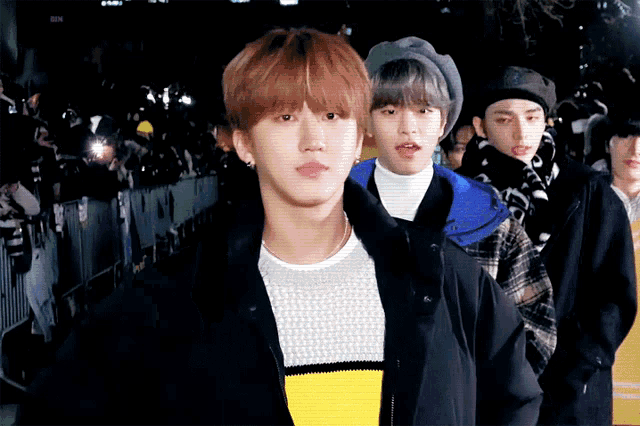 a group of young men are standing in front of a crowd looking at the camera