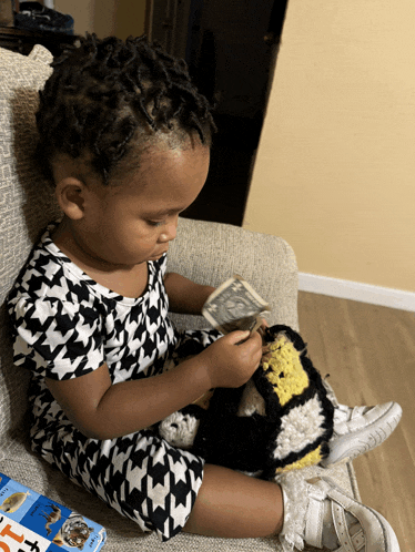 a little girl is sitting on a couch holding a dollar bill