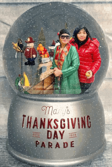 two women in a snow globe that says mary 's thanksgiving day parade on it