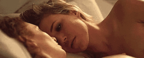 a man and a woman are laying in bed kissing each other .