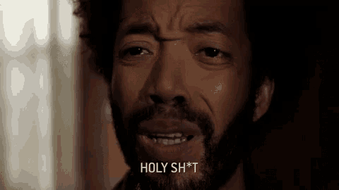 a man with a beard is making a face and saying holy shit .