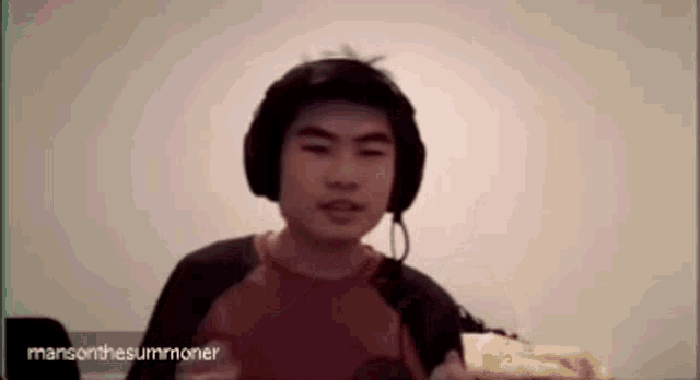 a young man wearing headphones is sitting in front of a screen .