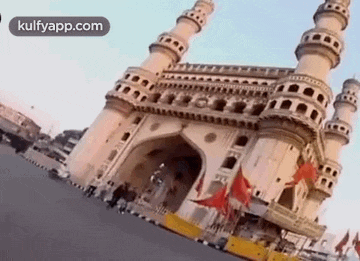 a large building with a lot of towers and flags in front of it