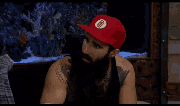 a man with a beard wearing a red hat says this isn 't a dating show while talking to a woman