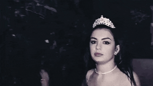 a girl wearing a tiara is sticking out her tongue .