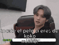 a man with gray hair is sitting in a chair and talking to someone in spanish .
