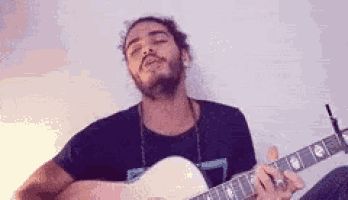 a man with a beard is playing a guitar and singing into it .