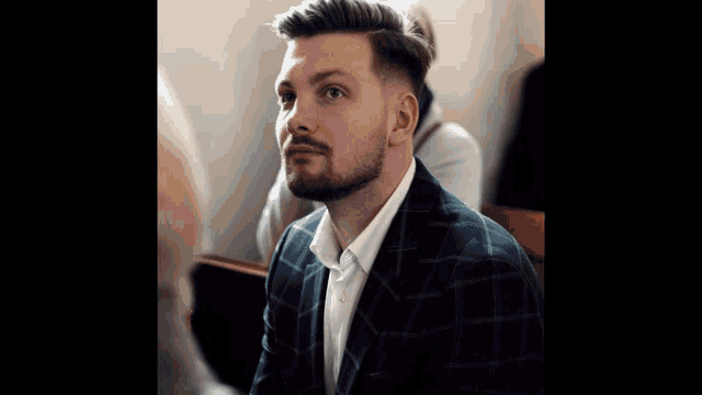 a man with a beard is wearing a suit