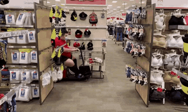 a man in a red shirt is pushing a shopping cart in a clothing store