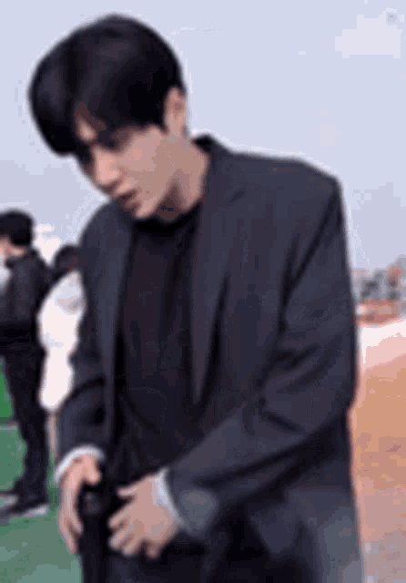 a man in a suit and black shirt is holding a camera in his hand .