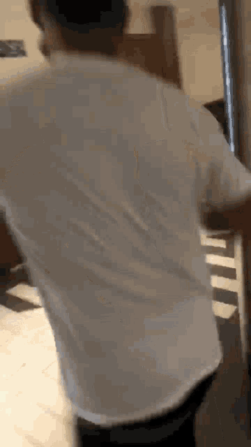 a man in a white shirt is standing in a room .