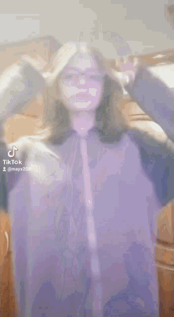 a girl wearing glasses and a purple jacket is dancing in a tiktok video