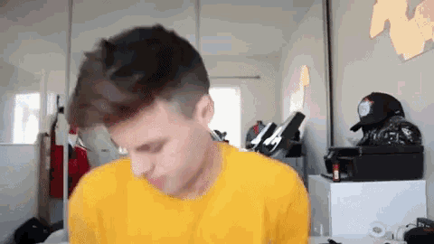a man in a yellow shirt is standing in a room