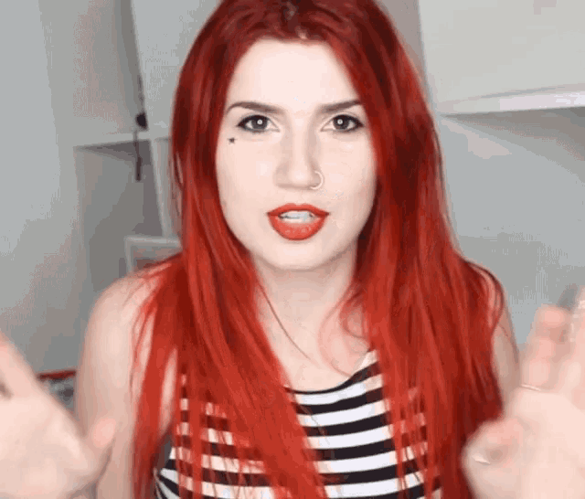 a woman with red hair is wearing a striped shirt and red lipstick