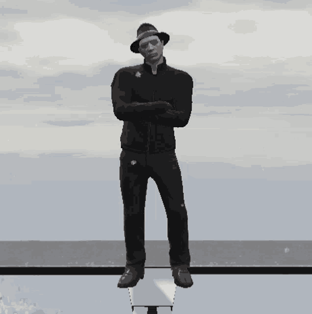 a man wearing a hat and sunglasses is standing on a ledge with his arms crossed