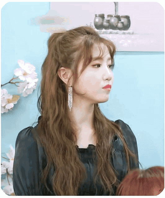 a woman wearing a black shirt and earrings looks to the side