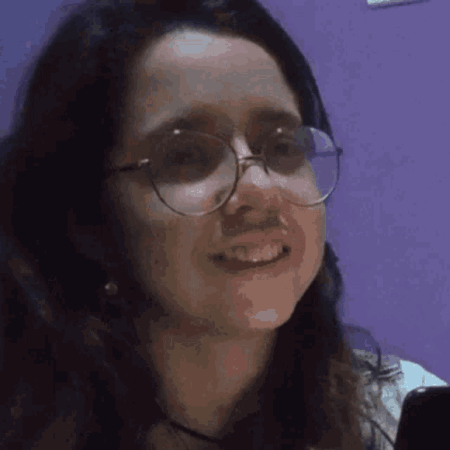 a woman wearing glasses and a nose ring is smiling .