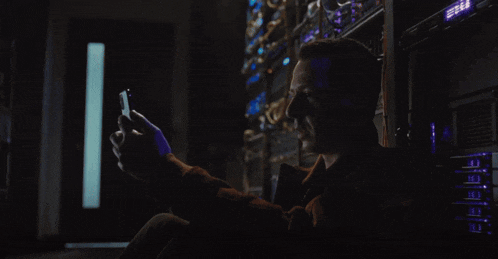 a man in a dark room is looking at a cell phone