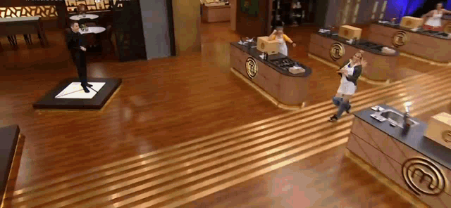a man and woman are dancing in a kitchen with a master chef logo on the counter
