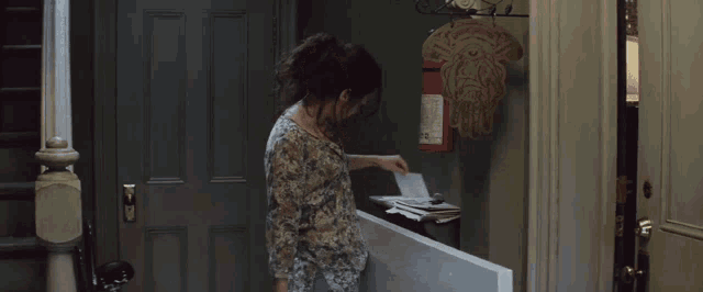 a woman is putting a piece of paper into a mailbox that has the number 2 on it