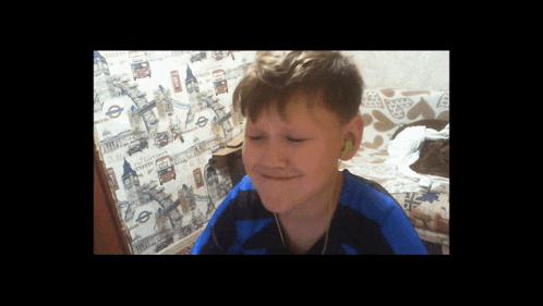 a young boy wearing ear buds is sitting in front of a wall with a london sign on it