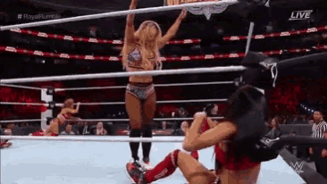 two women are wrestling in a ring with a referee .
