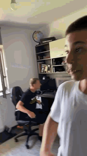 a man is standing next to another man in a room with a desk .