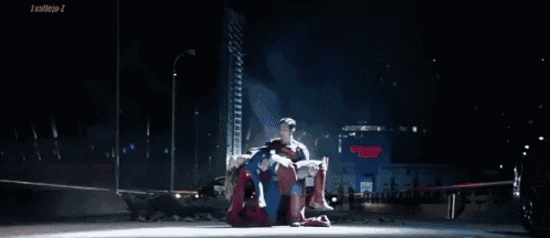 a man in a superman suit is holding another man in a red suit