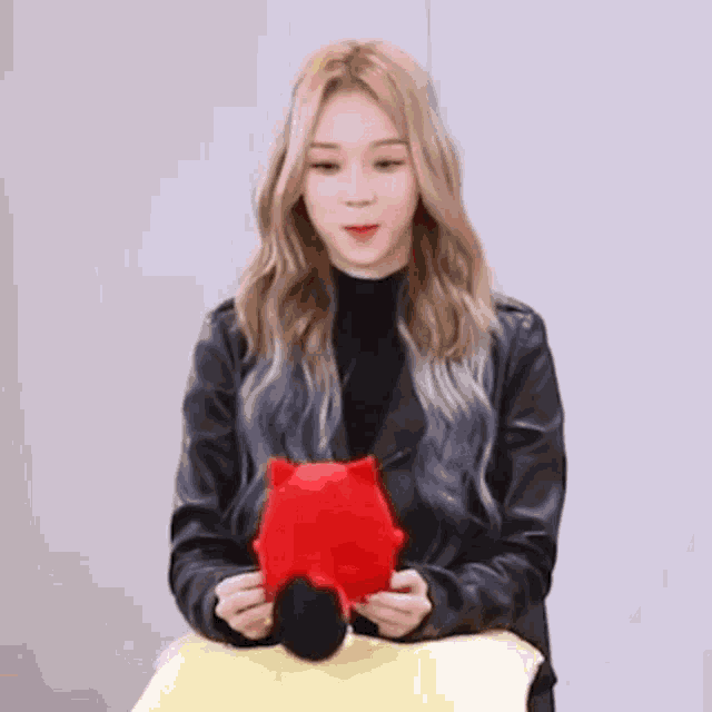 a woman in a black jacket is holding a stuffed animal .