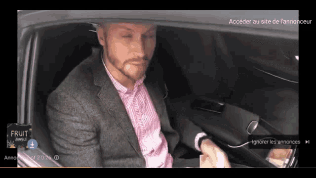 a man in a suit is sitting in a car with an advertisement for fruit punch