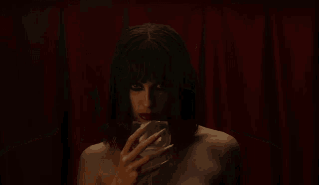 a woman drinking from a glass in a dark room