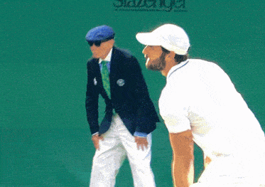 a man in a white shirt stands next to a man in a blue hat on a tennis court