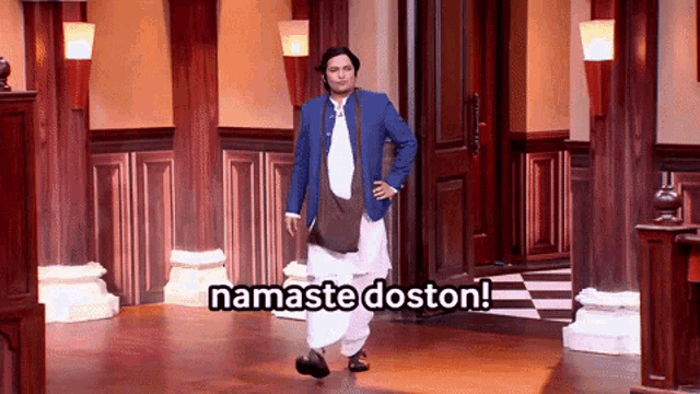 a man in a blue jacket is standing in a hallway with the words namaste doston above him