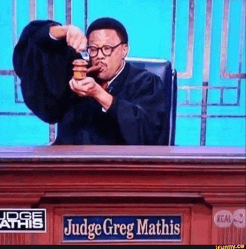 a man in a judge 's robe is sitting at a judge 's bench eating a hamburger .