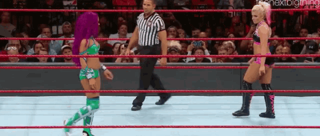 two women are wrestling in a wrestling ring with a referee standing between them .
