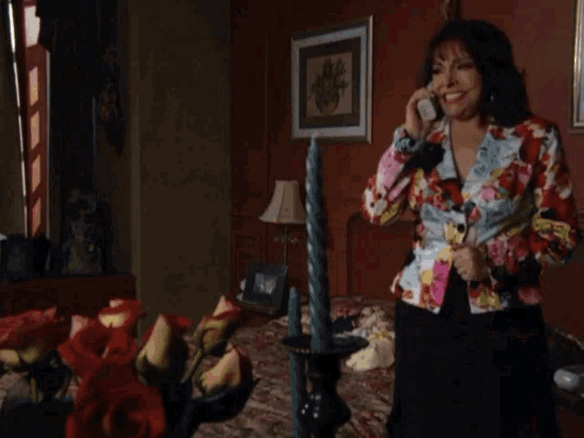 a woman in a colorful jacket is talking on a cell phone in a bedroom