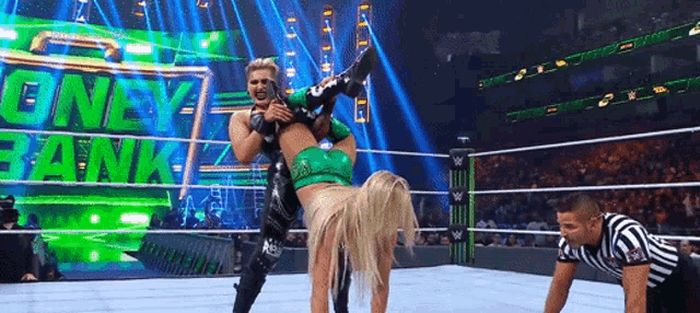 a wrestler is being lifted in the air by another wrestler while a referee looks on .