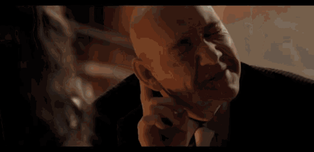 a bald man in a suit and tie is making a funny face .