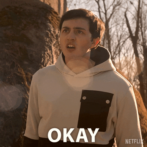 a man in a hoodie says okay in front of a rock