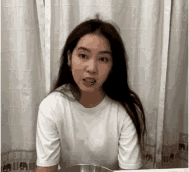 a woman with long hair is wearing a white shirt and has her tongue sticking out