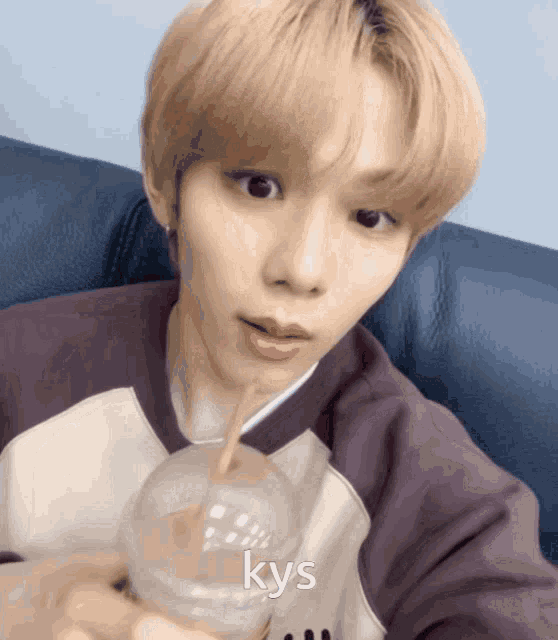 a young man holding a cup with a straw and the word kys written on it