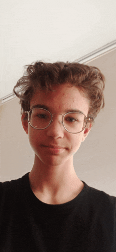 a boy wearing glasses and a black shirt looks at the camera