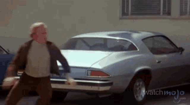a man is running towards a car that says watchmojo.com on it