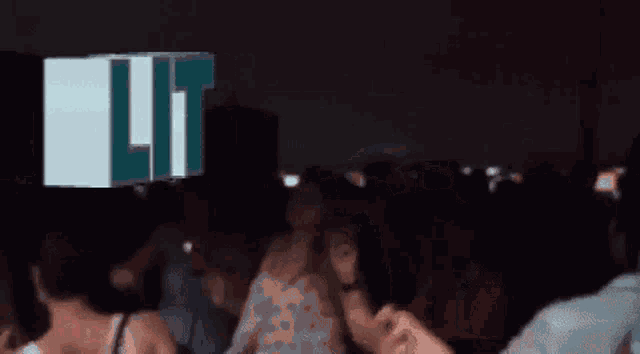 a group of people are dancing in a dark room with lit written in blue letters