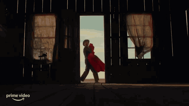 a man is holding a woman in his arms in front of a door that has the word prime video on it