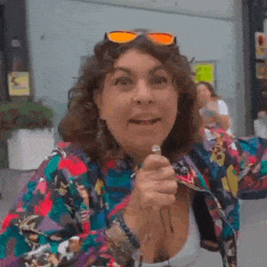 a woman wearing sunglasses and a colorful jacket is making a funny face .