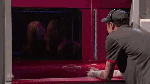a man in a hat is standing in front of a red truck .