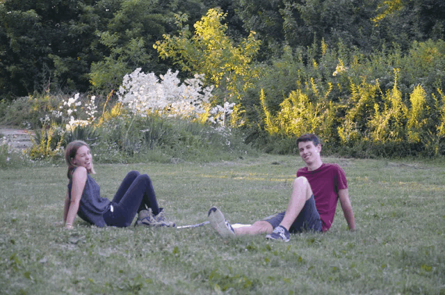 a man and a woman are sitting on the grass